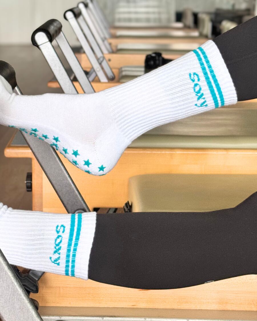 Chaussettes Soxy blanches à rayures turquoise sur un reformer